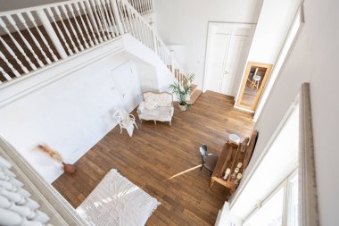 İki katlı, balkon tarzı dekoratif eşyalarla dolu, parlak bir dairede modern bir oda. Beyaz duvarlar, ahşap döşemeler ve eski mobilyalar.