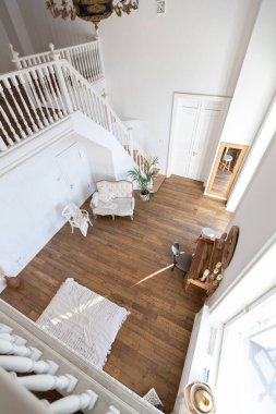 İki katlı, balkon tarzı dekoratif eşyalarla dolu, parlak bir dairede modern bir oda. Beyaz duvarlar, ahşap döşemeler ve eski mobilyalar.