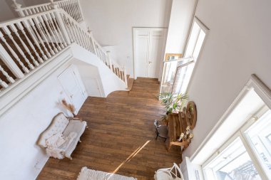 İki katlı, balkon tarzı dekoratif eşyalarla dolu, parlak bir dairede modern bir oda. Beyaz duvarlar, ahşap döşemeler ve eski mobilyalar.