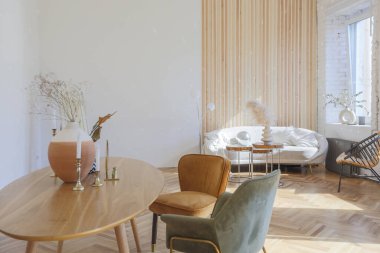 Ahşap elementleri ve beyaz duvarları olan geniş bir oturma odasının pahalı, hafif, lüks iç tasarımı. Orijinal ve alışılmadık dekoratif şeylerle dolu.