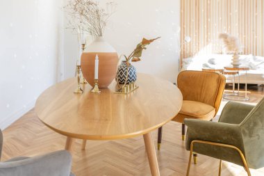 Ahşap elementleri ve beyaz duvarları olan geniş bir oturma odasının pahalı, hafif, lüks iç tasarımı. Orijinal ve alışılmadık dekoratif şeylerle dolu.