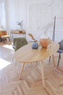 Ahşap elementleri ve beyaz duvarları olan geniş bir oturma odasının pahalı, hafif, lüks iç tasarımı. Orijinal ve alışılmadık dekoratif şeylerle dolu.