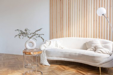 Ahşap elementleri ve beyaz duvarları olan geniş bir oturma odasının pahalı, hafif, lüks iç tasarımı. Orijinal ve alışılmadık dekoratif şeylerle dolu.