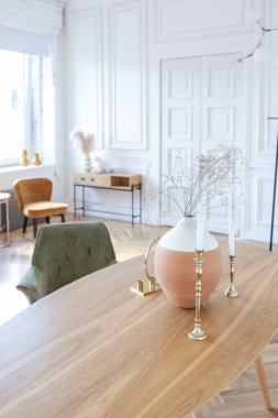 Ahşap elementleri ve beyaz duvarları olan geniş bir oturma odasının pahalı, hafif, lüks iç tasarımı. Orijinal ve alışılmadık dekoratif şeylerle dolu.