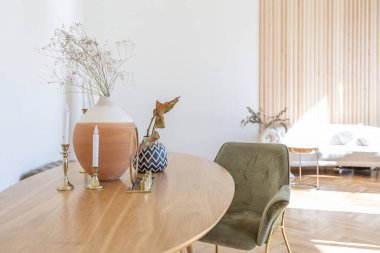 Ahşap elementleri ve beyaz duvarları olan geniş bir oturma odasının pahalı, hafif, lüks iç tasarımı. Orijinal ve alışılmadık dekoratif şeylerle dolu.