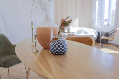 Ahşap elementleri ve beyaz duvarları olan geniş bir oturma odasının pahalı, hafif, lüks iç tasarımı. Orijinal ve alışılmadık dekoratif şeylerle dolu.