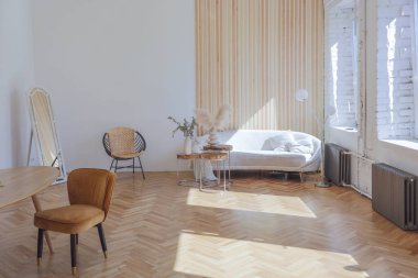 Ahşap elementleri ve beyaz duvarları olan geniş bir oturma odasının pahalı, hafif, lüks iç tasarımı. Orijinal ve alışılmadık dekoratif şeylerle dolu.