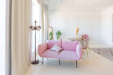 Oturma odasının iç kısmı hassas ve rahat. Pastel pembe renkli modern şık mobilyalar ve gündüz sıva pervazlı beyaz duvarlar.