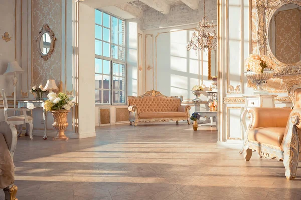 rich apartment interior with golden baroque decorations on the walls and luxury furniture. the room is flooded with the rays of the setting sun
