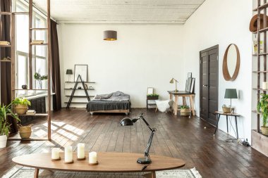 Ahşap ve beyazla dekore edilmiş geniş bir stüdyo daire. Minimalist tasarım ve güneş ışığı altında kocaman pencereler. Mutfak ve yaşam alanı