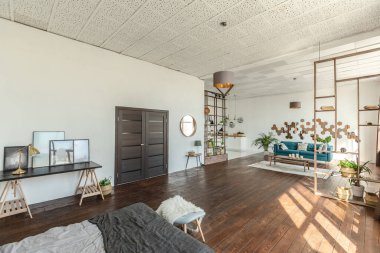 Ahşap ve beyazla dekore edilmiş geniş bir stüdyo daire. Minimalist tasarım ve güneş ışığı altında kocaman pencereler. Mutfak ve yaşam alanı