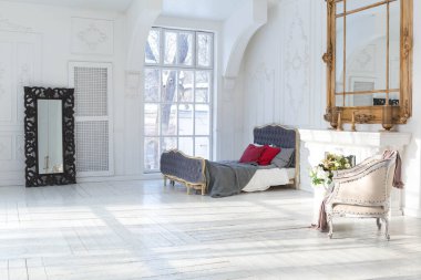 Geniş, parlak bir oturma odası. Modern tasarımı, antika dekorları ve eski tarz şık mobilyaları ve yerden tavana kadar birçok penceresi var.