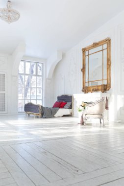 Geniş, parlak bir oturma odası. Modern tasarımı, antika dekorları ve eski tarz şık mobilyaları ve yerden tavana kadar birçok penceresi var.