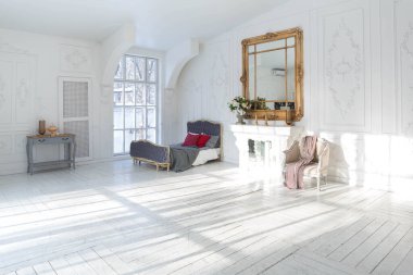 Geniş, parlak bir oturma odası. Modern tasarımı, antika dekorları ve eski tarz şık mobilyaları ve yerden tavana kadar birçok penceresi var.