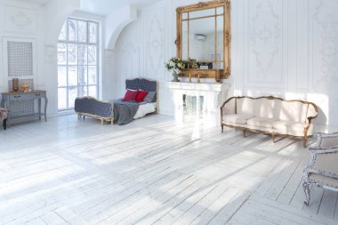 Geniş, parlak bir oturma odası. Modern tasarımı, antika dekorları ve eski tarz şık mobilyaları ve yerden tavana kadar birçok penceresi var.