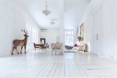 Geniş, parlak bir oturma odası. Modern tasarımı, antika dekorları ve eski tarz şık mobilyaları ve yerden tavana kadar birçok penceresi var.