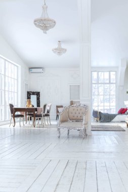 Geniş, parlak bir oturma odası. Modern tasarımı, antika dekorları ve eski tarz şık mobilyaları ve yerden tavana kadar birçok penceresi var.