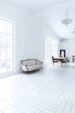 Geniş, parlak bir oturma odası. Modern tasarımı, antika dekorları ve eski tarz şık mobilyaları ve yerden tavana kadar birçok penceresi var.