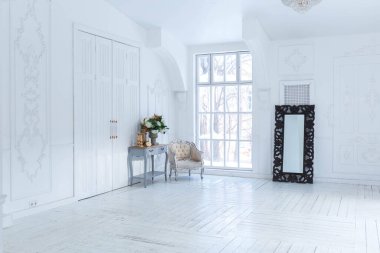 Geniş, parlak bir oturma odası. Modern tasarımı, antika dekorları ve eski tarz şık mobilyaları ve yerden tavana kadar birçok penceresi var.