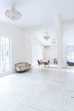 Geniş, parlak bir oturma odası. Modern tasarımı, antika dekorları ve eski tarz şık mobilyaları ve yerden tavana kadar birçok penceresi var.