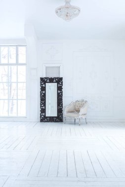 Geniş, parlak bir oturma odası. Modern tasarımı, antika dekorları ve eski tarz şık mobilyaları ve yerden tavana kadar birçok penceresi var.