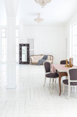 Geniş, parlak bir oturma odası. Modern tasarımı, antika dekorları ve eski tarz şık mobilyaları ve yerden tavana kadar birçok penceresi var.