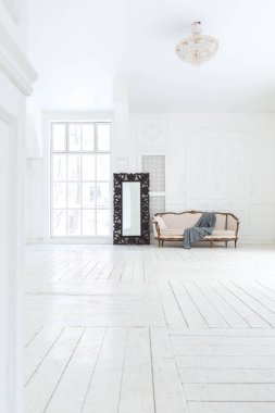 Geniş, parlak bir oturma odası. Modern tasarımı, antika dekorları ve eski tarz şık mobilyaları ve yerden tavana kadar birçok penceresi var.