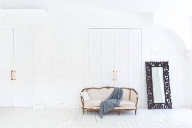 Geniş, parlak bir oturma odası. Modern tasarımı, antika dekorları ve eski tarz şık mobilyaları ve yerden tavana kadar birçok penceresi var.