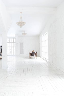 Geniş, parlak bir oturma odası. Modern tasarımı, antika dekorları ve eski tarz şık mobilyaları ve yerden tavana kadar birçok penceresi var.