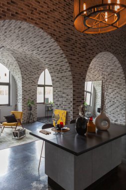 Ortaçağ şatosu tarzında parlak aksanlı, vahşi bir apartman dairesinin modern lüks tasarımı. Yemek pişirmek ya da zaman geçirmek için bir adası olan şık gri bir mutfak.