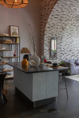 Ortaçağ şatosu tarzında parlak aksanlı, vahşi bir apartman dairesinin modern lüks tasarımı. Yemek pişirmek ya da zaman geçirmek için bir adası olan şık gri bir mutfak.