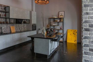 Ortaçağ şatosu tarzında parlak aksanlı, vahşi bir apartman dairesinin modern lüks tasarımı. Yemek pişirmek ya da zaman geçirmek için bir adası olan şık gri bir mutfak.