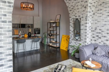 Ortaçağ şatosu tarzında parlak aksanlı, vahşi bir apartman dairesinin modern lüks tasarımı. Yemek pişirmek ya da zaman geçirmek için bir adası olan şık gri bir mutfak.