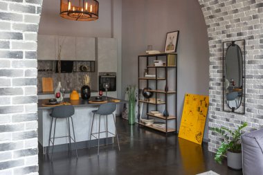 Ortaçağ şatosu tarzında parlak aksanlı, vahşi bir apartman dairesinin modern lüks tasarımı. Yemek pişirmek ya da zaman geçirmek için bir adası olan şık gri bir mutfak.