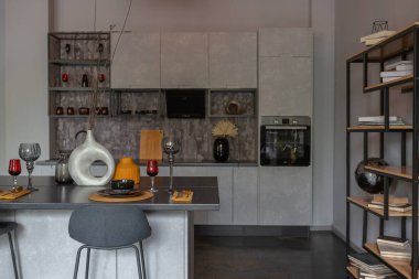 Ortaçağ şatosu tarzında parlak aksanlı, vahşi bir apartman dairesinin modern lüks tasarımı. Yemek pişirmek ya da zaman geçirmek için bir adası olan şık gri bir mutfak.