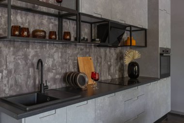 Ortaçağ şatosu tarzında parlak aksanlı, vahşi bir apartman dairesinin modern lüks tasarımı. Yemek pişirmek ya da zaman geçirmek için bir adası olan şık gri bir mutfak.