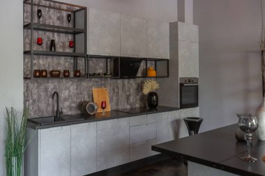 Ortaçağ şatosu tarzında parlak aksanlı, vahşi bir apartman dairesinin modern lüks tasarımı. Yemek pişirmek ya da zaman geçirmek için bir adası olan şık gri bir mutfak.