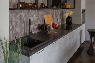 Ortaçağ şatosu tarzında parlak aksanlı, vahşi bir apartman dairesinin modern lüks tasarımı. Yemek pişirmek ya da zaman geçirmek için bir adası olan şık gri bir mutfak.