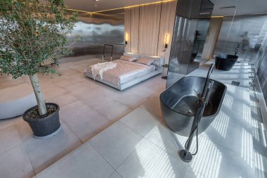 Japon tarzı bej ve siyah renklerde modern minimalist yumuşak tasarım odası. Panjurları olan büyük bir panoramik pencerenin yanında şık bir şekilde ayrılmış bir banyo.