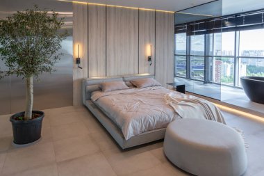 Japon tarzı bej ve siyah renklerde modern minimalist yumuşak tasarım odası. Panjurları olan büyük bir panoramik pencerenin yanında şık bir şekilde ayrılmış bir banyo.