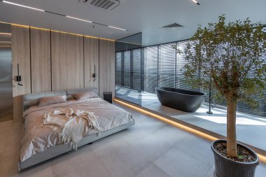 Japon tarzı bej ve siyah renklerde modern minimalist yumuşak tasarım odası. Panjurları olan büyük bir panoramik pencerenin yanında şık bir şekilde ayrılmış bir banyo.