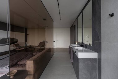 Modern LED ışıklandırmalı ve şık mobilyalı prestijli lüks otelin pahalı iç tasarımı. Lavabosu olan alan yatak odasından koyu camla ayrılmış.