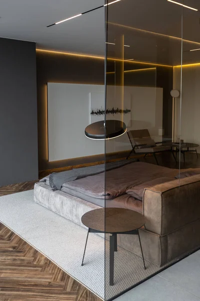 モダンなLed照明とスタイリッシュな家具と暗い色調で権威ある高級ホテルの部屋のクールな高価なインテリアデザイン シンク付きの領域は寝室から暗いガラスで区切られています — ストック写真