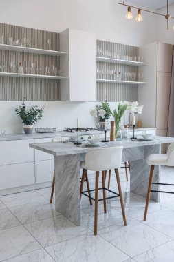 Yakın manzaralı mutfak, yemek masası ve minimalist hafif bar tabureleri yumuşak pastel bej renkli modern geniş bir stüdyo dairesinin lüks tasarımı.