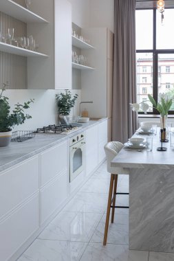 Yakın manzaralı mutfak, yemek masası ve minimalist hafif bar tabureleri yumuşak pastel bej renkli modern geniş bir stüdyo dairesinin lüks tasarımı.