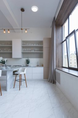 Yakın manzaralı mutfak, yemek masası ve minimalist hafif bar tabureleri yumuşak pastel bej renkli modern geniş bir stüdyo dairesinin lüks tasarımı.
