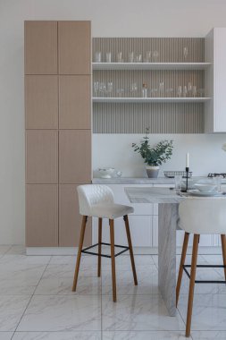 Yakın manzaralı mutfak, yemek masası ve minimalist hafif bar tabureleri yumuşak pastel bej renkli modern geniş bir stüdyo dairesinin lüks tasarımı.