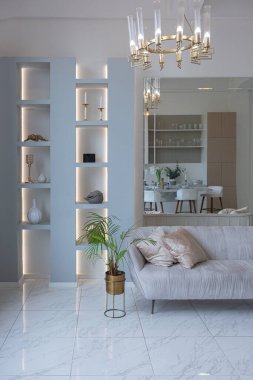 Mutfak alanı, yatak odası ve kanepenin arkasında kocaman aynası olan modern geniş bir stüdyo dairesinin minimalist hafif zarif tasarımı. Zeminde fayanslar ve yüksek tavan.