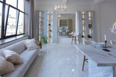 Mutfak alanı, yatak odası ve kanepenin arkasında kocaman aynası olan modern geniş bir stüdyo dairesinin minimalist hafif zarif tasarımı. Zeminde fayanslar ve yüksek tavan.