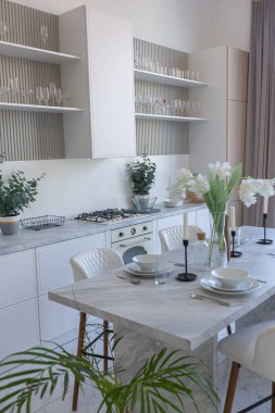 Yakın manzaralı mutfak, yemek masası ve minimalist hafif bar tabureleri yumuşak pastel bej renkli modern geniş bir stüdyo dairesinin lüks tasarımı.
